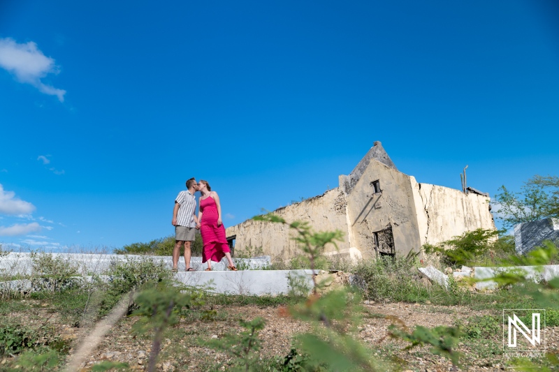 Couple enjoying a romantic moment near the historical ruins in Landhuis San Juan, Curacao under a bright blue sky