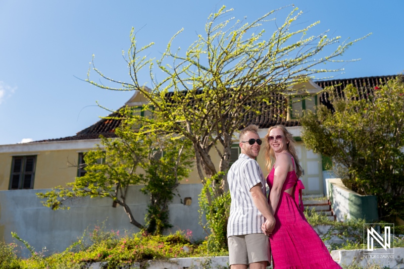 Romantic couple enjoying the sunny day at Landhuis San Juan, Curacao, with vibrant surroundings and lush greenery