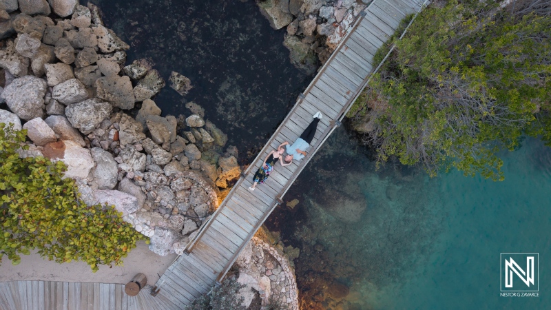 Couple enjoys photoshoot on wooden dock at Baoase Luxury Resort in Curacao during sunset