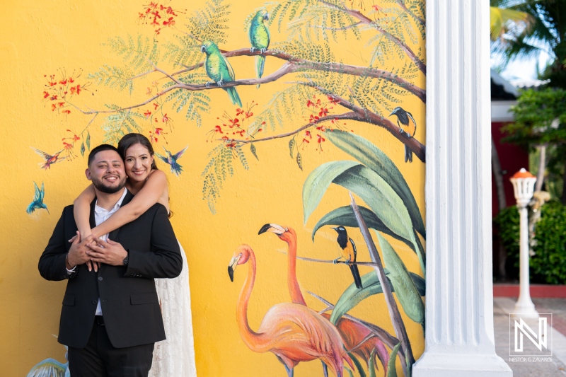 Couple celebrates engagement in vibrant Curacao with colorful mural backdrop featuring tropical birds and lush plants