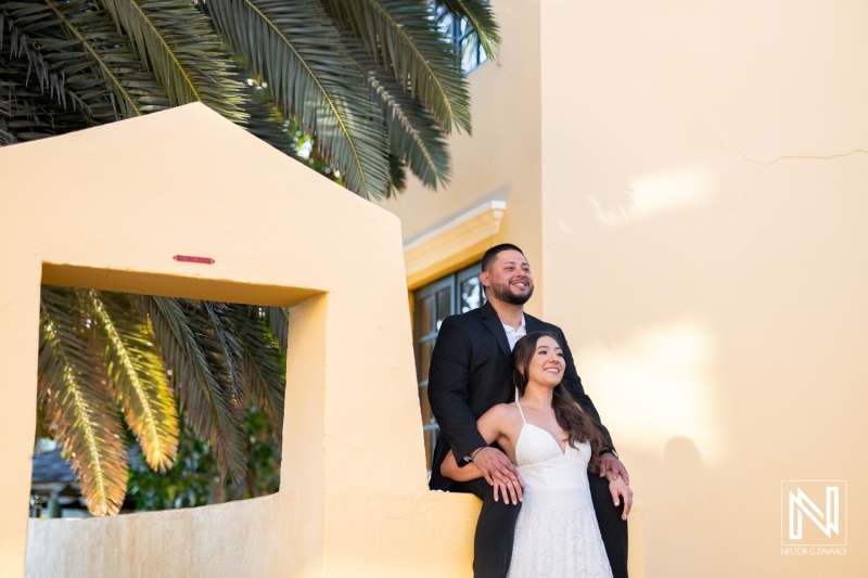 Engagement celebration in Curacao, featuring a couple enjoying a sunny moment near vibrant architecture and palm trees