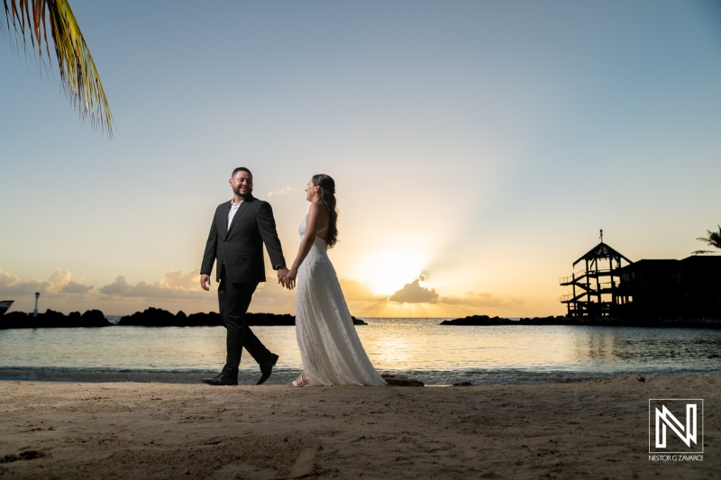 Couple walks hand in hand on the beach at sunset during a joyous engagement celebration in Curacao