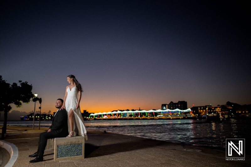 Engagement celebration by the sea in Curacao at sunset with beautifully illuminated buildings in the background