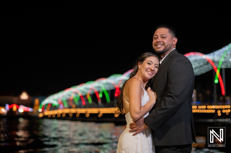 Couple celebrates engagement in beautiful Curacao at night with colorful bridge lights in the background