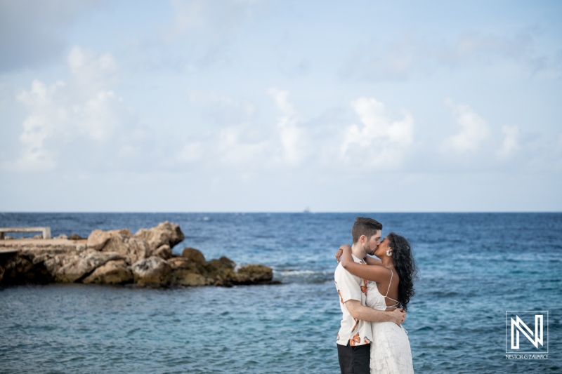 Couple enjoying engagement session at Marie Pampoen in Curacao with ocean in background under blue sky