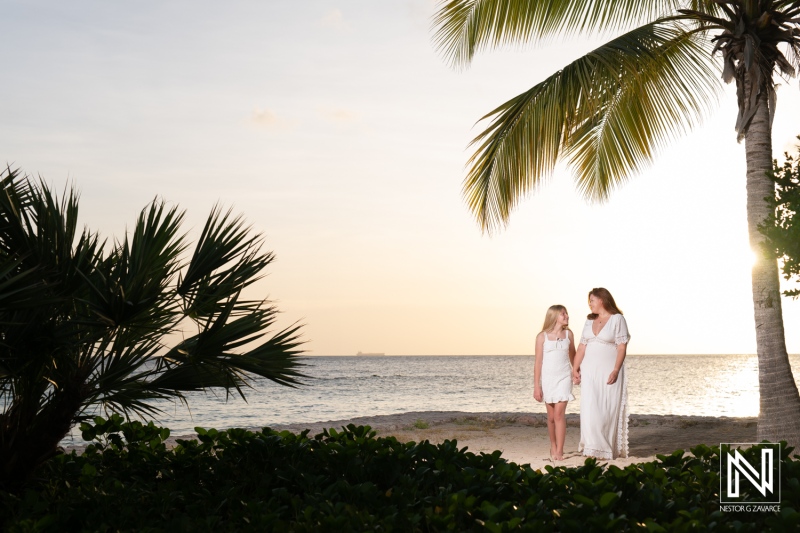 Family enjoying a sunset on the beach in Curacao with palm trees and waves creating a serene atmosphere