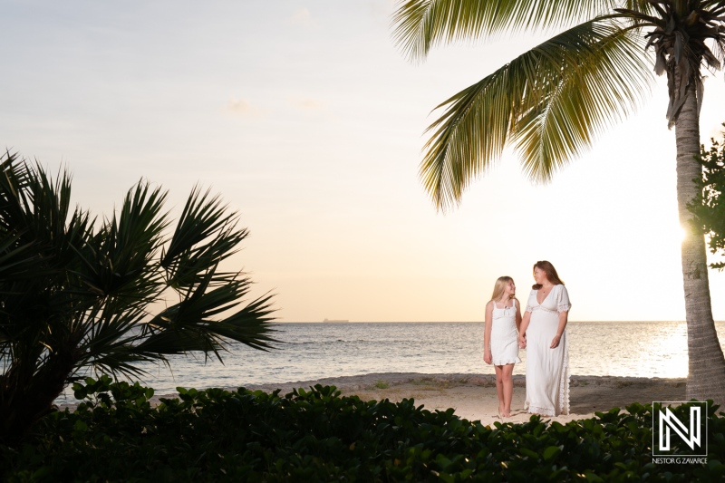 Family enjoying a sunset on the beach in Curacao with palm trees and waves creating a serene atmosphere