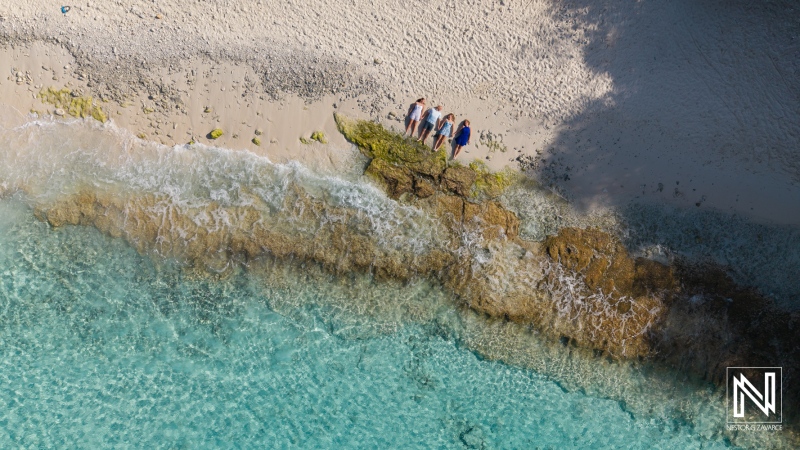 Family and friends enjoying a day at the beach in Curacao while exploring the rocky shoreline and appreciating the clear water