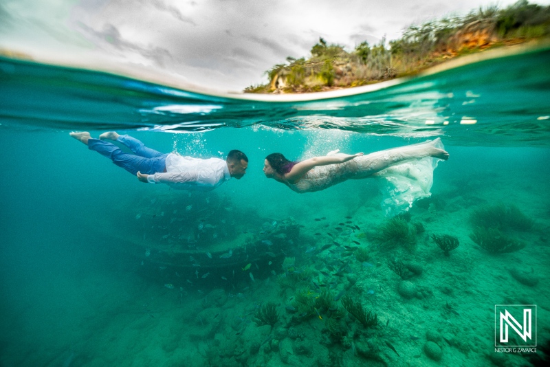 Couple embraces underwater adventure during trash the dress session in Curacao's crystal-clear waters