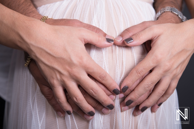 Maternity moment captured in Curacao with hands forming heart shape around a pregnant belly