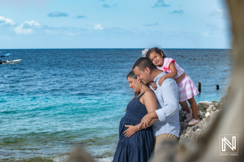 Couple joyfully celebrating maternity on the beautiful shores of Curacao with their daughter during the golden hour