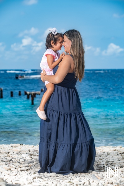 Pregnant woman embracing her daughter at the beach in Curacao during a sunny day, celebrating motherhood and love