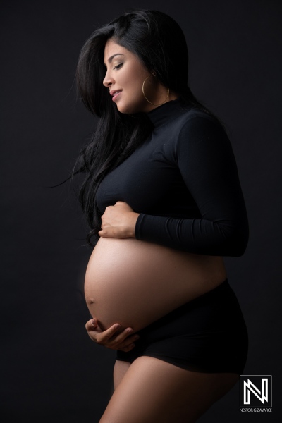 Radiant expectant mother showcasing her baby bump in a serene maternity portrait in Curacao