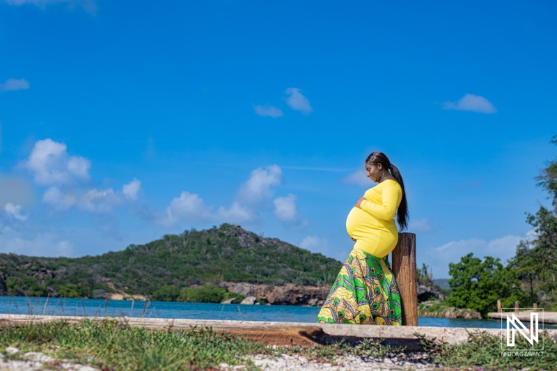 Beautiful maternity moment on the beach in Curacao during pregnancy with a scenic backdrop of island hills and blue sky