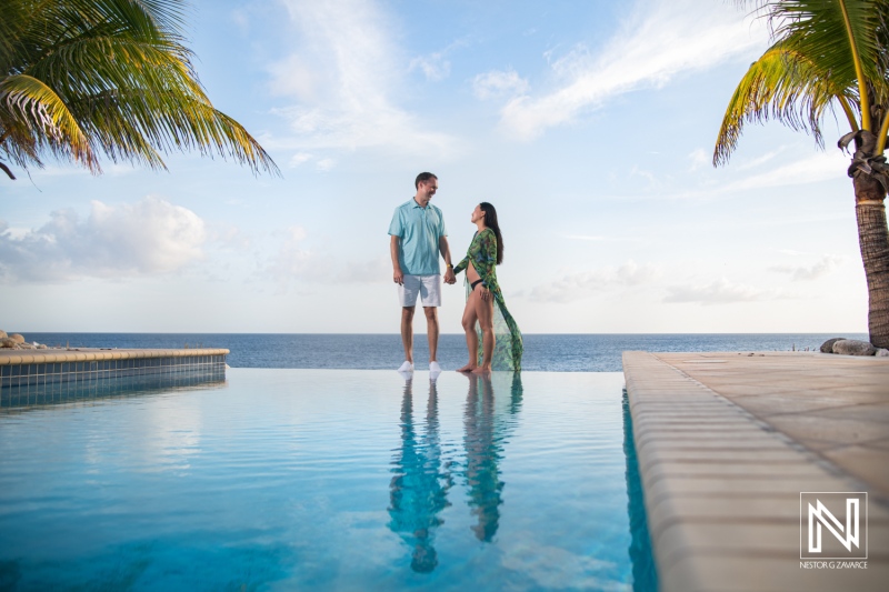 Couple enjoys a romantic moment by the serene waters of Curacao during pregnancy celebration