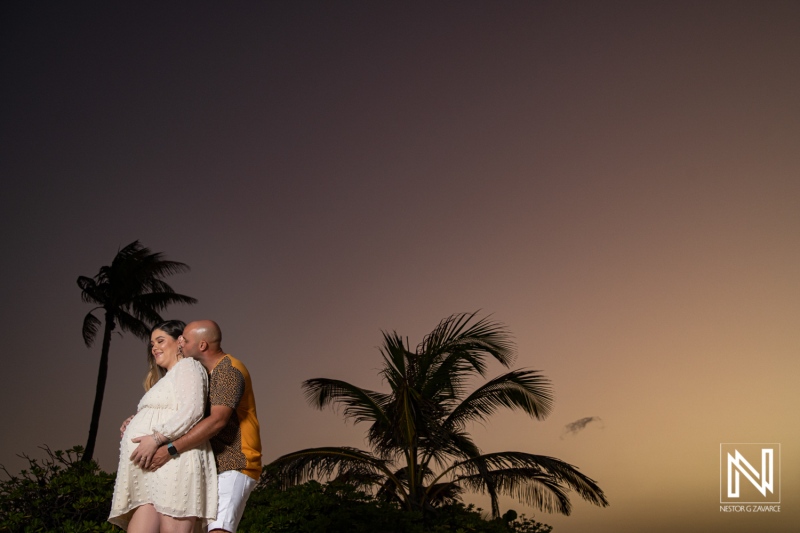 Expecting parents enjoying a serene sunset in Curacao during a maternity photoshoot