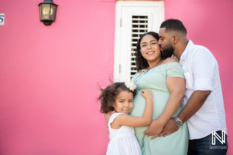 Celebration of pregnancy and family joy in Curacao during maternity photoshoot with pink backdrop