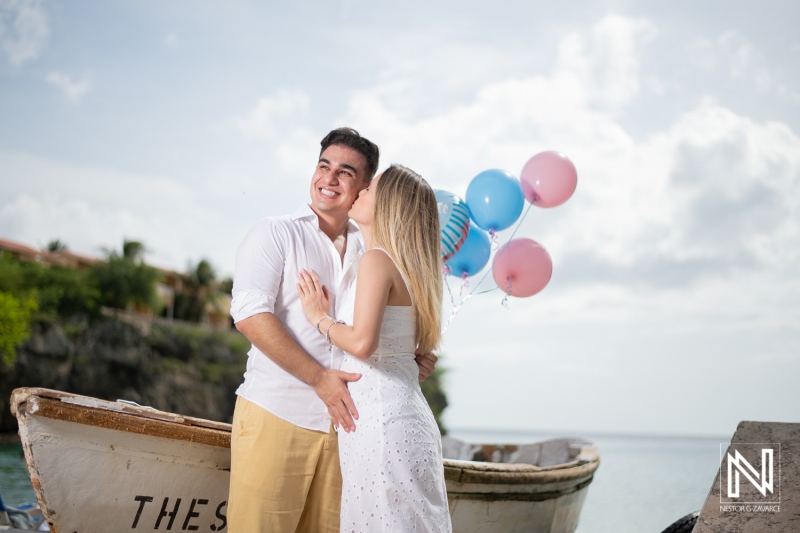 Maternity celebration in Curacao with colorful balloons and a happy couple enjoying a serene moment by the water