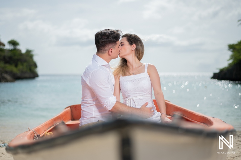 Couple sharing a romantic kiss in a boat on the beach in Curacao during a maternity photoshoot