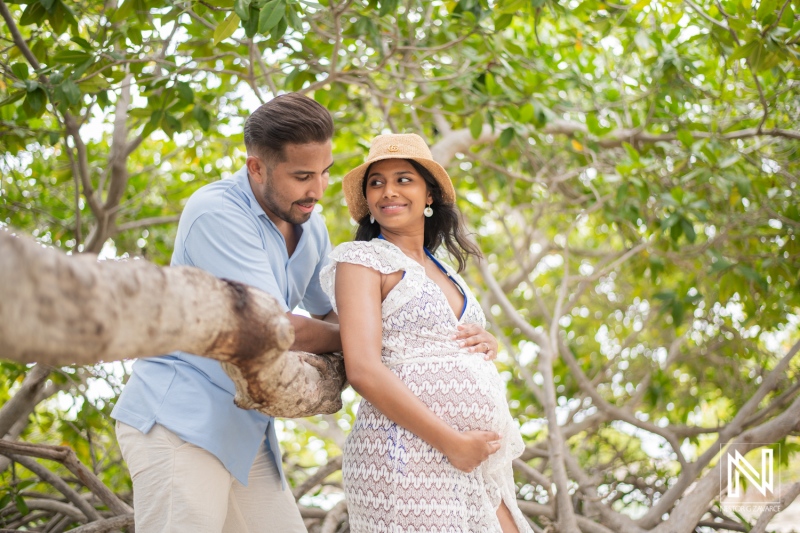 Couple enjoying a serene moment together under lush greenery in Curacao while celebrating maternity and the joys of pregnancy