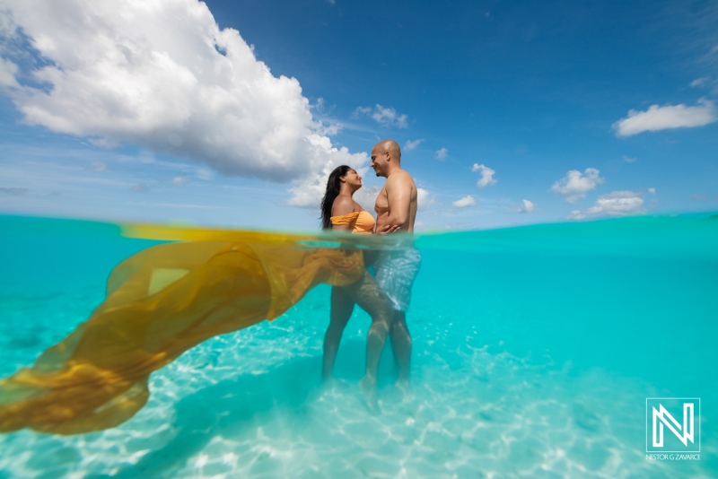 Maternity couple enjoying a joyful moment in the clear waters of Curacao under a bright blue sky during their pregnancy celebration