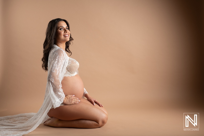 Celebrating maternal beauty in Curacao with a graceful maternity pose amidst a soft backdrop