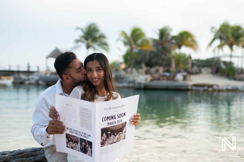 Couples maternity announcement by the water in Curacao during sunset, capturing joyful anticipation of a new family member