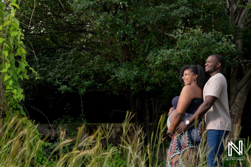 Expecting parents joyfully enjoying a sunny day in Curacao's lush landscape while celebrating pregnancy