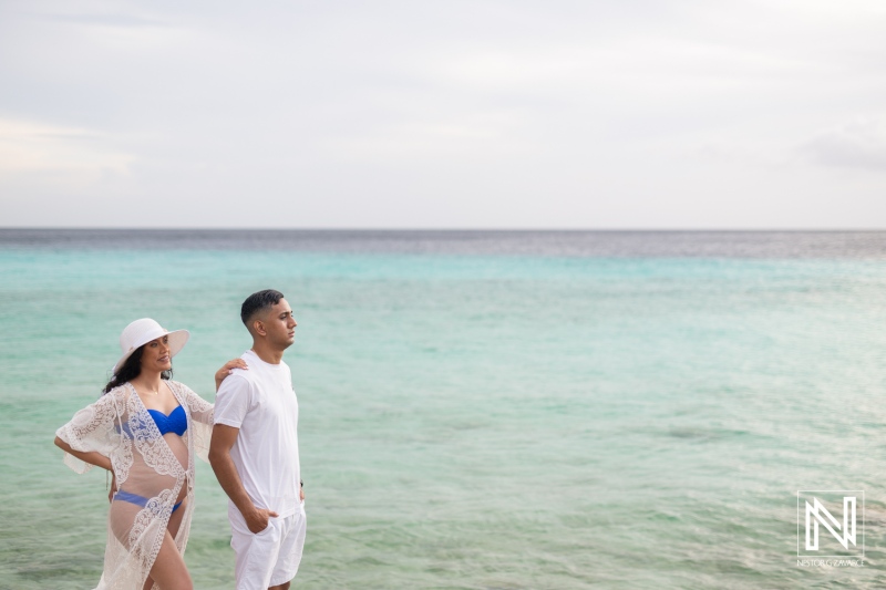 Maternity photoshoot on the beautiful shores of Curacao showcases expectant parents enjoying the serene beach setting during golden hour
