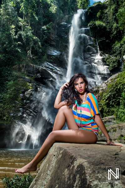 A woman in a colorful outfit sitting by a waterfall in a lush green forest during a sunny day, enjoying nature\'s beauty and relaxing by the water