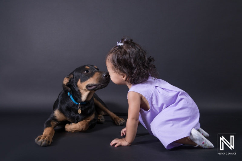 A young child interacts with a friendly dog in a playful moment indoors captured against a dark background