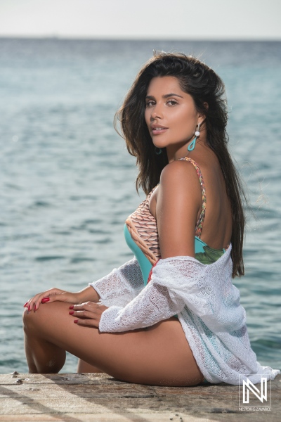 Woman in a white cover-up sitting by the water, enjoying a sunny day at the beach surrounded by the ocean\'s calm waves during midday