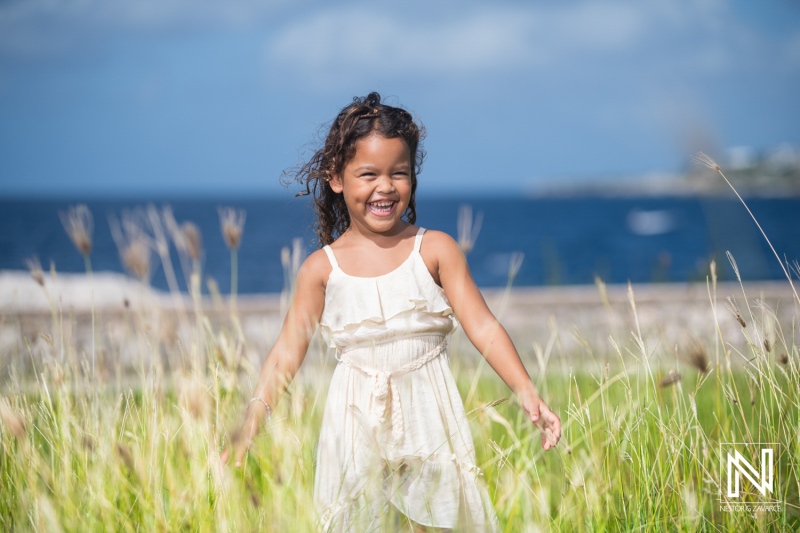 A joyful girl plays in a field of tall grass by the ocean in a sunny afternoon, showcasing her excitement and carefree spirit on a beautiful day