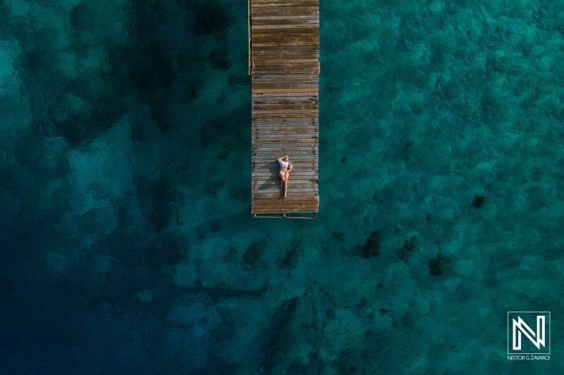 Relaxing on a wooden dock surrounded by clear blue water during a sunny day on a tropical island