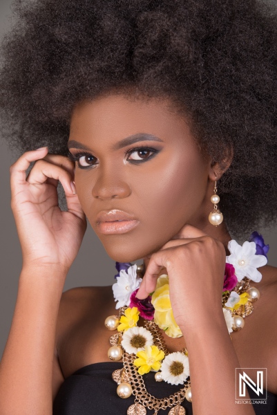 A young woman poses with confidence, showcasing vibrant accessories and bold makeup in a studio setting