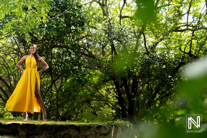 A woman in a vibrant yellow dress stands gracefully in a lush green forest, enjoying the sunlight on a beautiful day during the spring season