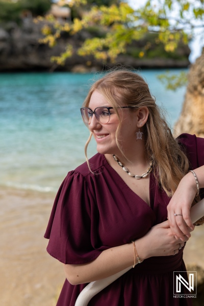 Portrait of a model by the shoreline in Curacao during a sunny afternoon, showcasing vibrant beach scenery and elegant fashion