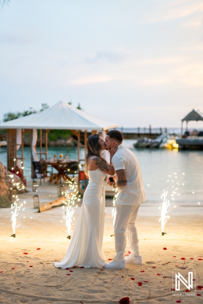 Wedding proposal at Baoase Luxury Resort in Curacao features groom and bride sharing a kiss with fireworks in the background during sunset