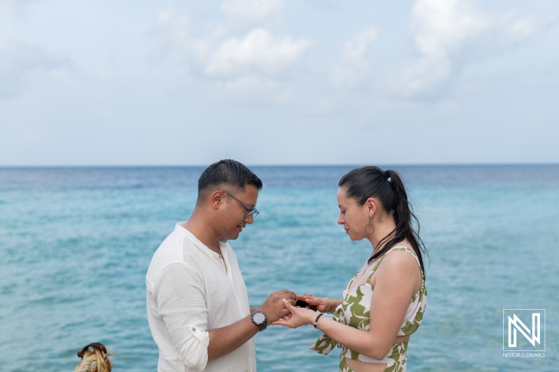 Romantic wedding proposal at Kokomo Beach in Curacao captures a couple exchanging rings with the ocean in the background