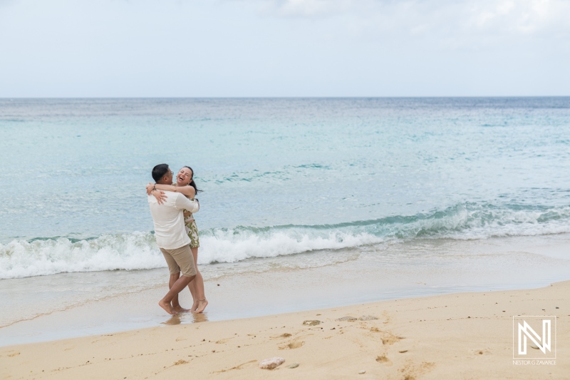 Couple celebrates engagement at Kokomo Beach in Curacao with joyful embrace and stunning ocean backdrop under a serene sky
