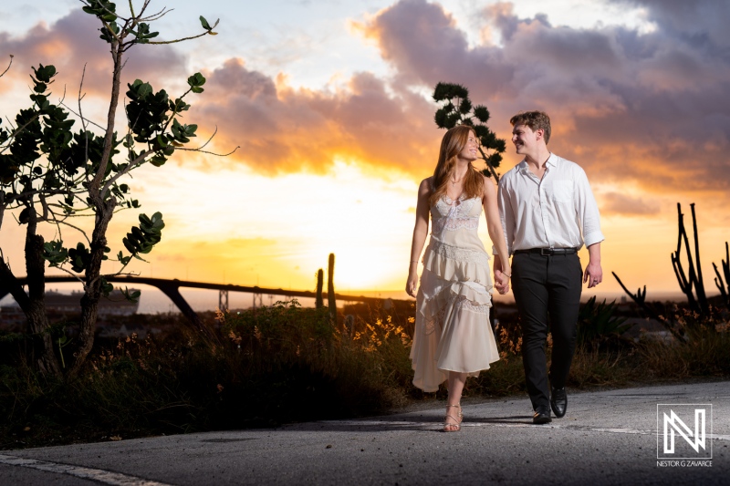 Couple walks hand in hand during wedding proposal at Fort Nassau in Curacao at sunset