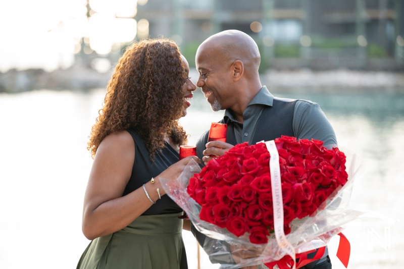 Couple shares a special moment during a wedding proposal at Avila Beach Hotel in Curacao with a large bouquet of roses