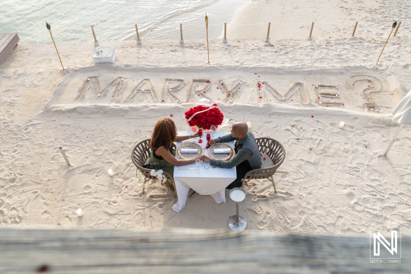 Couple enjoys a wedding proposal on the beach at Avila Beach Hotel in Curacao with a romantic setup in the sand
