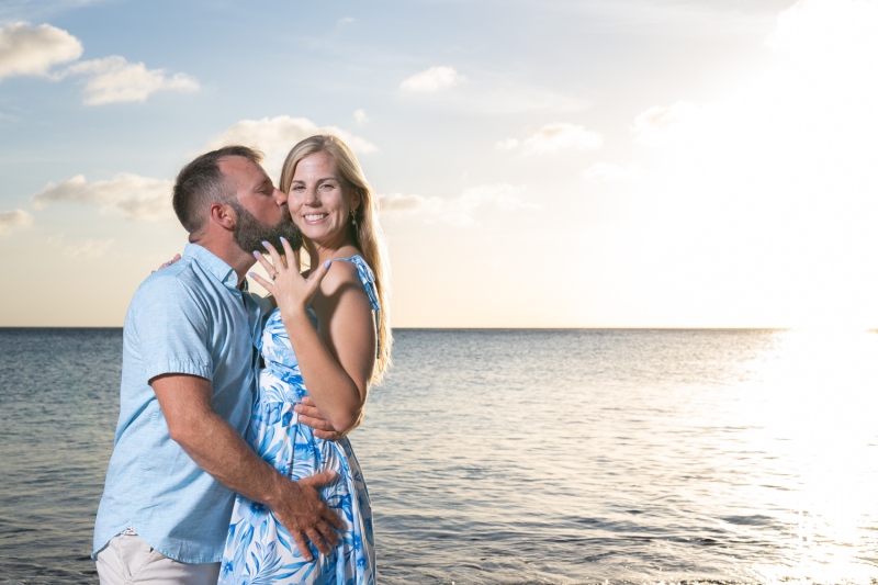 Couple enjoys a romantic sunset proposal at Playa Jeremi in Curacao, capturing a joyful moment by the tranquil sea