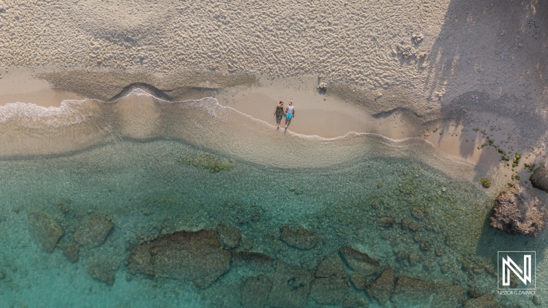 Couple celebrates a romantic wedding proposal during sunrise at Daaibooi Beach in Curacao, surrounded by beautiful coastal scenery