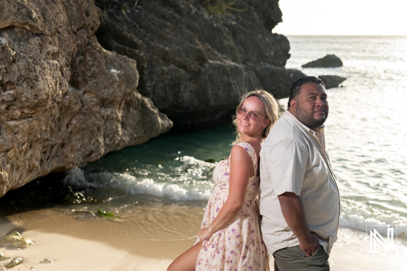 A couple enjoys a sunny day at the beach near rocky cliffs, creating cherished memories by the serene ocean waves at sunset