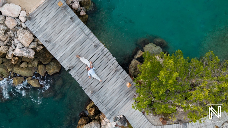 Couple celebrates engagement on wooden dock at Baoase Luxury Resort in Curacao during sunny day