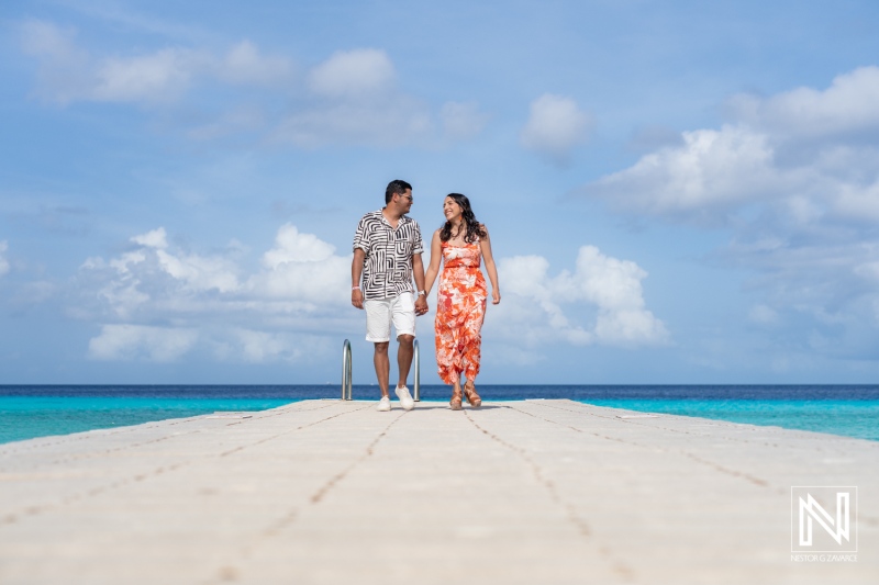 A Couple Walks Hand in Hand Along a Beautiful Pier Overlooking the Turquoise Waters of a Tropical Beach During a Sunny Day