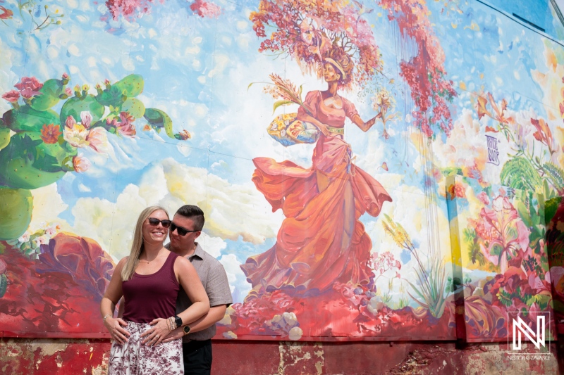 Couple shares a wedding proposal moment in front of a colorful mural in Willemstad, Curacao during a sunny day