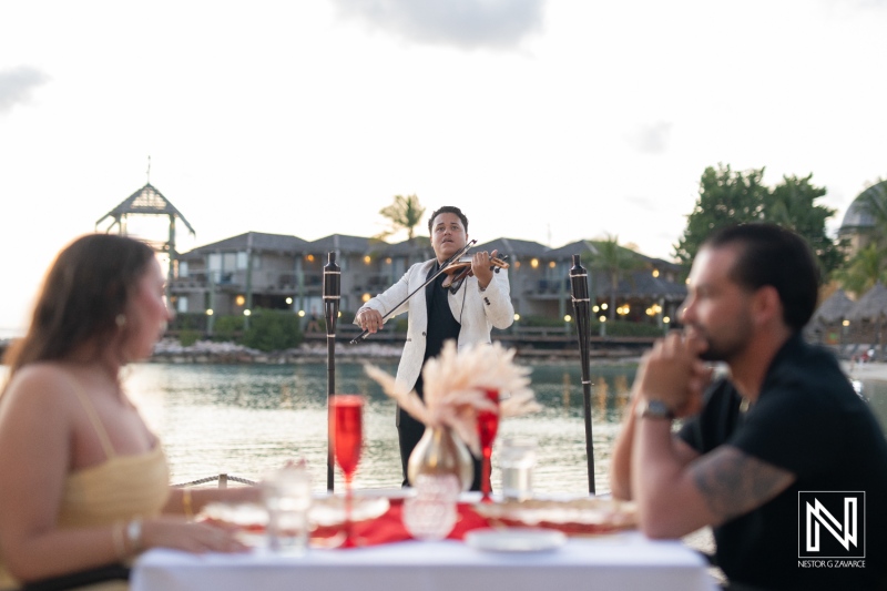 Couple enjoys sunset wedding proposal serenaded by violinist at Avila Beach Hotel in Curacao